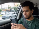 Motorista consultando notificação de multa de trânsito pelo celular em São Carlos